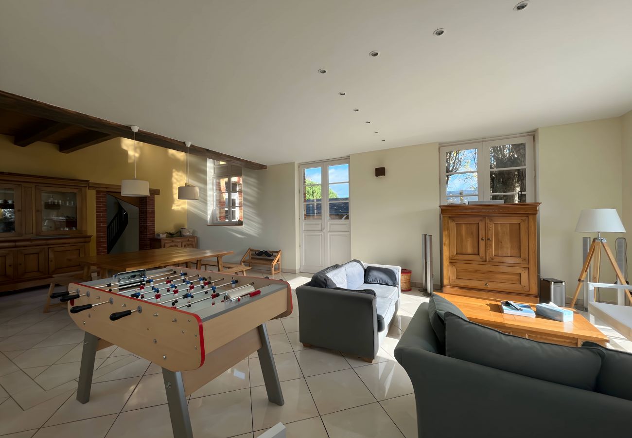 Salon confortable de la Villa L'Ecolière avec canapé, baby-foot, table en chêne, meuble élégant et éclairage soigné