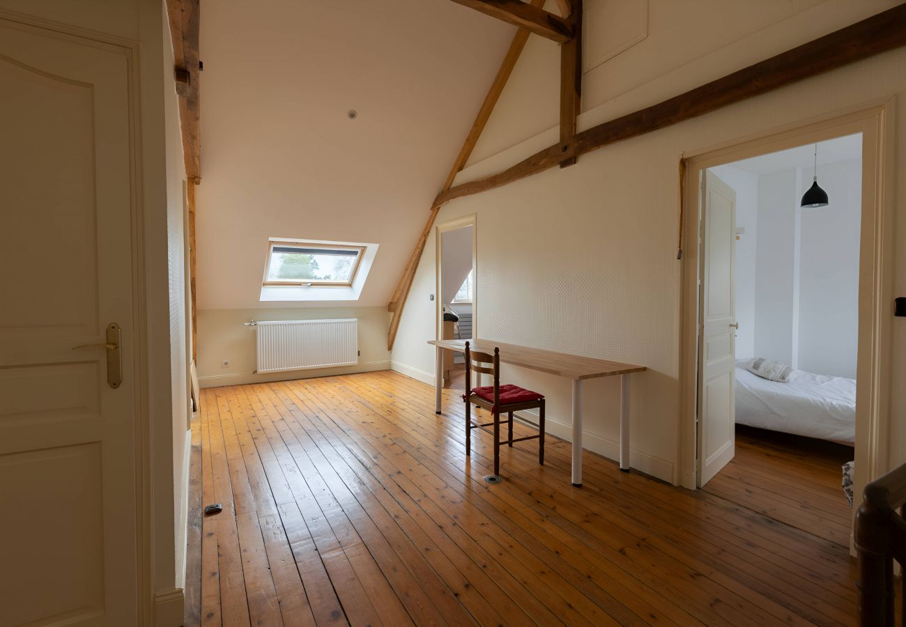 Vue depuis l'escalier sur l'étage de la Villa L'Ecolière : parquet, bureau, portes des chambres, poutres de toiture.