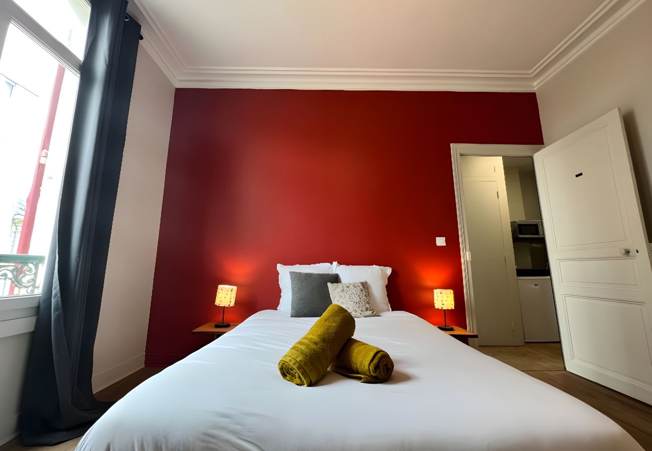 Chambre avec lit double, tables de chevet, lampes et grande fenêtre à Au Soleil Levant