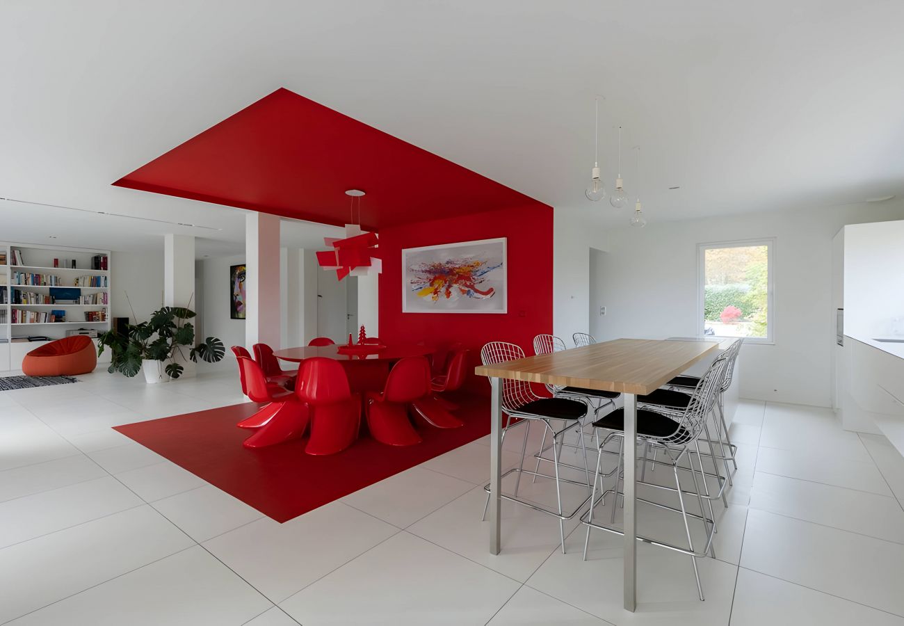 Table haute de la cuisine avec chaises hautes, deuxième table rouge, luminaires vintage avec ampoules suspendues