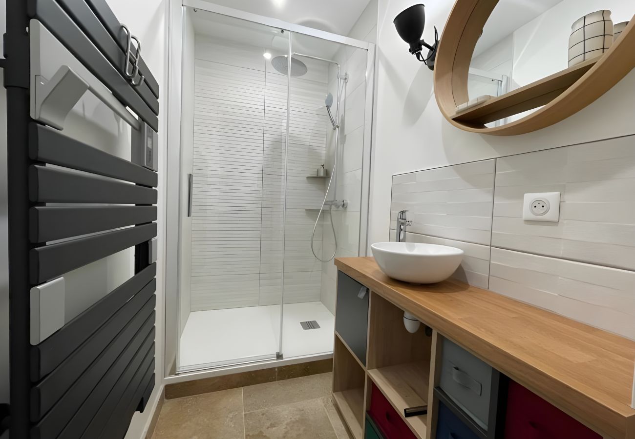 Salle de bain avec douche à l'italienne, vasque élégante et miroir éclairé.